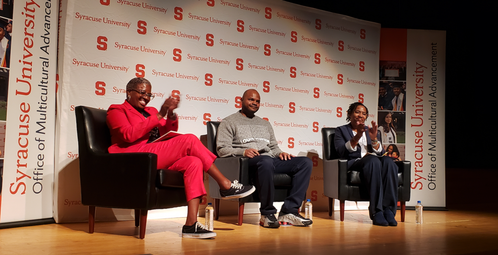 Three adults sitting as panelists on stage